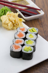 Sushi set on a white plate over vintage wooden background