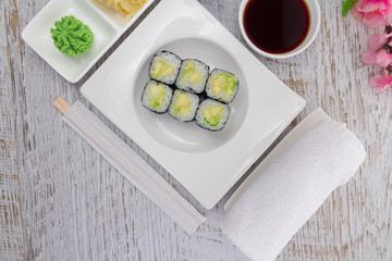 Japanese cuisine. Sushi on a white plate over vintage wooden background.