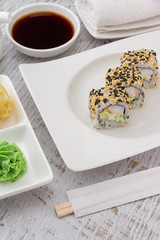 Obraz na płótnie Canvas Japanese cuisine. Sushi on a white plate over vintage wooden background.