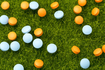 Orange and blue pills spilling on the green grass