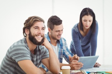 Fototapeta na wymiar Smiling man looking away with coworkers using digital tablet 