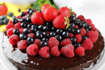 Delicious chocolate cake with summer berries on white wooden table, closeup