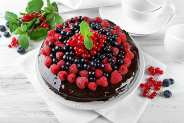 Delicious chocolate cake with summer berries on wooden table, closeup