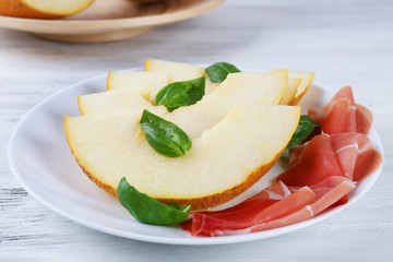 Melon with prosciutto of Parma ham on wooden table, closeup