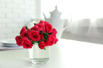 Beautiful flowers in vase on table, on light background