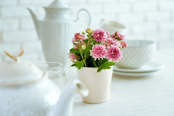Beautiful flowers in decorative vase on table, on light background