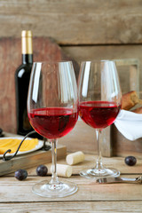 Still life of wine, grape, cheese and bread on rustic wooden background