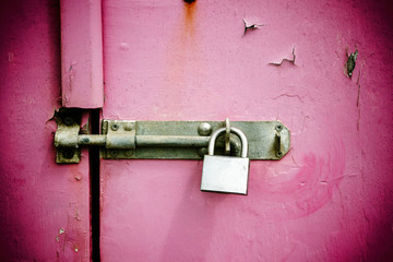 Rusty padlock on old pink painted wooden door