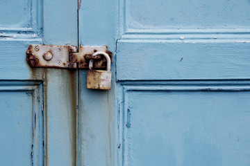 Rusty padlock on old painted wooden door