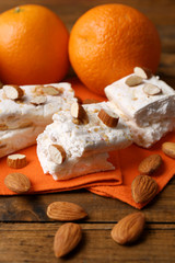 Sweet nougat with almonds and oranges on table close up