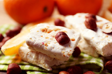 Sweet nougat with hazelnuts and oranges on table close up