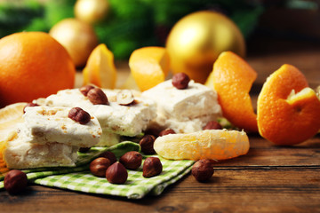 Sweet nougat with oranges and Christmas decoration  on table close up