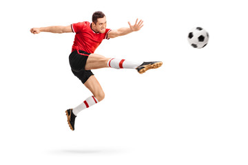 Fototapeta na wymiar Football player kicking a ball in mid-air