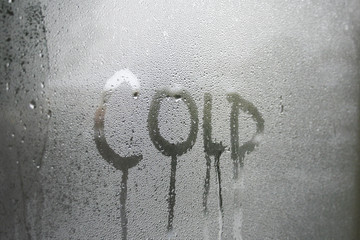 Cold text written in condensation on glass window pane
