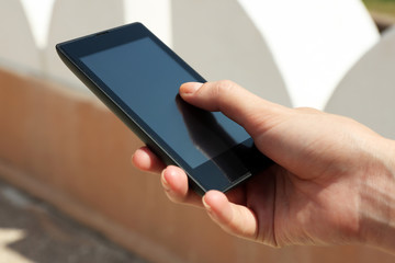 Female hand holding smart mobile phone outdoors