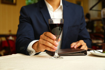 Young attractive man at the restaurant. Focus on wine glass