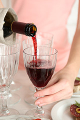 Woman pouring wine into glass, close up