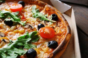 Pizza in box on wooden table closeup