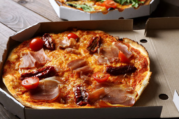 Pizza in box on wooden table closeup