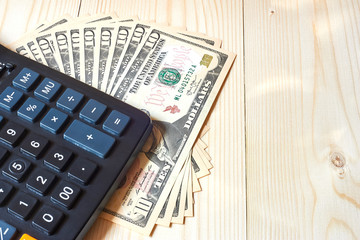 Calculator and dollars on a wooden background