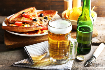 Sliced pizza served with beer on wooden table