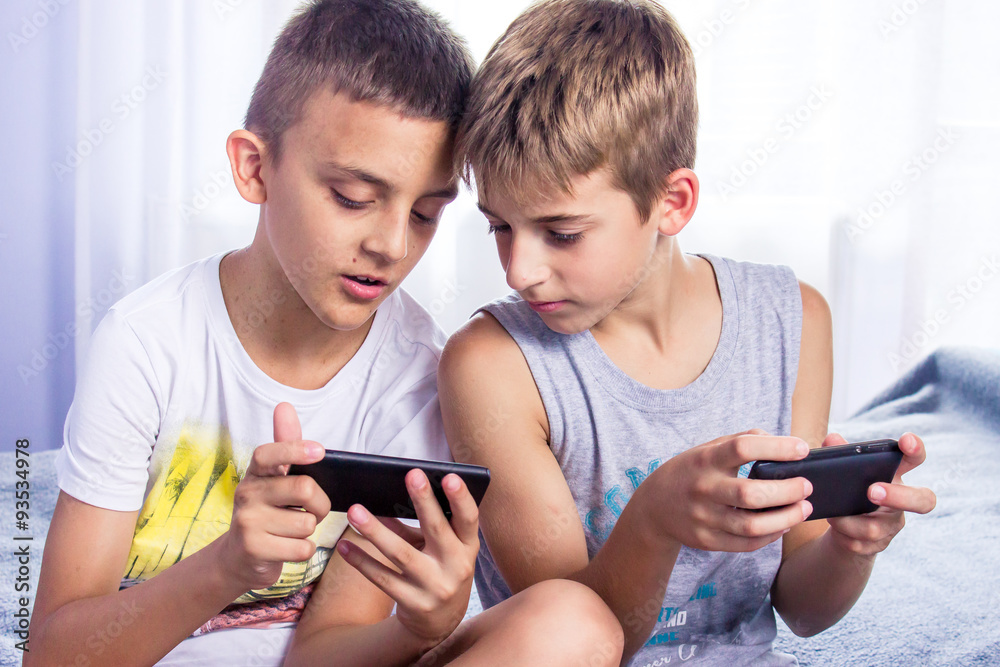 Wall mural cute boys playing games on cellphones. white background, horizontal orientation.