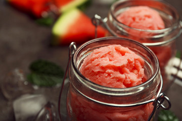 Watermelon ice cream in glass jars on dark background