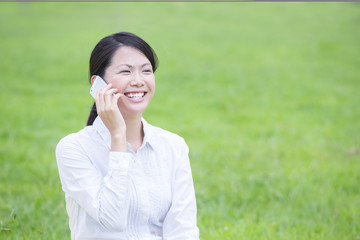 草原で電話する若い女性
