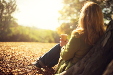 Autumn concept, anonymous woman enjoying takeaway coffee cup on sunny cols fall day