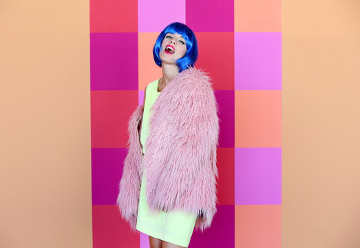 Young woman with blue hair on bright wall background