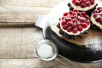 Sweet cakes with raspberries on wooden table background