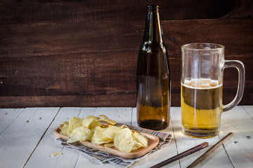 beer in glass with snack potato chips  on wooden background