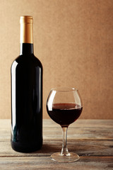 A bottle of red wine and a glass on wooden table