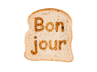 Word bonjour (meaning good morning in French) written on a toasted slice of bread © Delphotostock