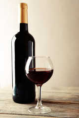 A bottle of red wine and a glass on wooden table