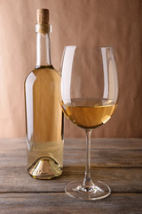 A bottle of white wine and a glass on wooden table