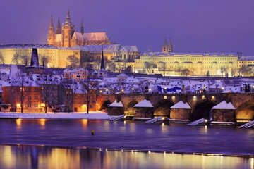 Night snowy Prague gothic Castle and St. Nicholas' Cathedral with Charles Bridge, Czech republic