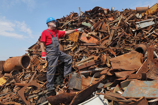 Recycling industry, worker gesture at heap of old metal