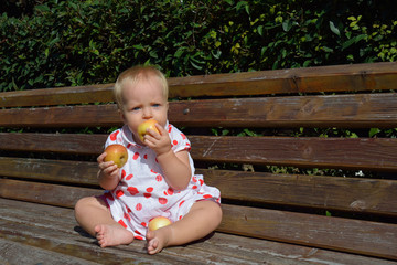 a blonde little girl eat two apples