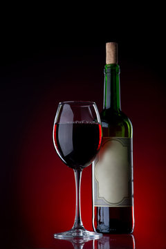 Wine and glass against a black background with red light