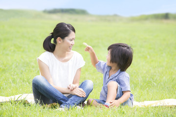 草原で電話する女性と遊ぶ子供