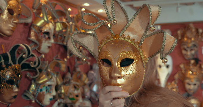 Woman in the store trying on golden Venetian mask