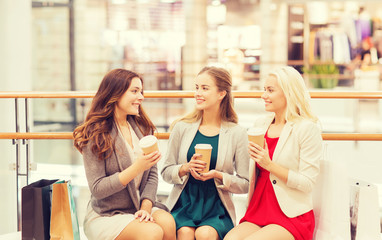 young women with shopping bags and coffee in mall