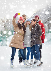 happy friends with smartphone on ice skating rink