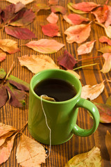 autumn leaves and tea cup over wood background
