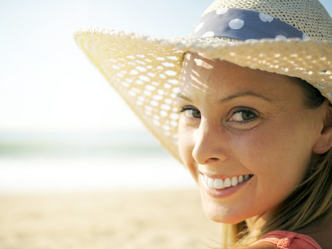 happy girl smiling portrait in the beach  wearing a picture hat with the sea and horizon in the background