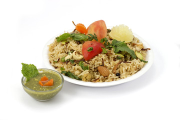 Indian Cuisine Veg Biryani (Vegetable Pulao) topped with dry fruites, chopped tomatoes, lime and mint leaves; served with green chatni.