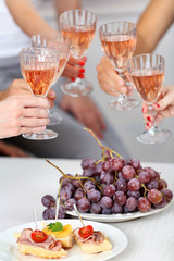 Friends hands with glasses of wine and snacks, close up
