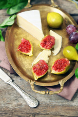Ripe figs and cheese on tray, on wooden background