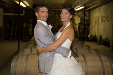 Newlywed couple in the wine cellar after their wedding looking at the camera